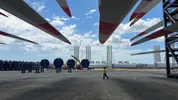 Een windmolenpark in aanbouw met grote windturbineonderdelen op een industrieterrein.