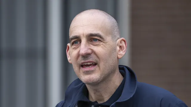 Jaïr Stranders spreekt vanachter een spreekgestoelte in een microfoon.