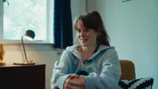 Een vrouw zit met haar knie tegen haar aan.