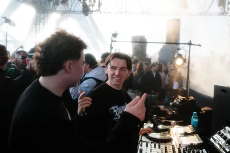 Twee mannen geven elkaar de hand achter de dj booth