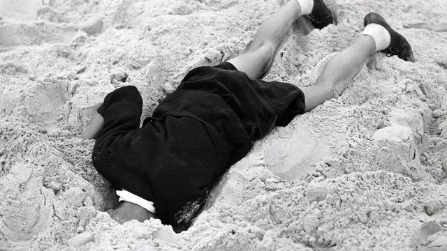 Schatgraven:Strandleven. Egmond aan Zee, Nederland: kind/jongen in het zand op het strand met zijn hoofd in een kuil, 26 augustus 1951.