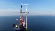 Installatie van een windturbine op zee, met meerdere windturbines op de achtergrond.