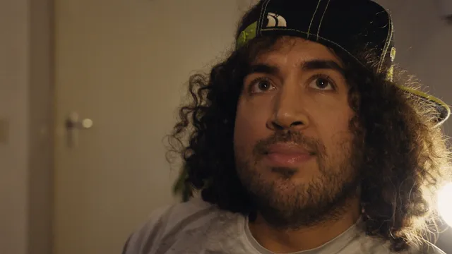 Een man met lang, donker haar kijkt aandachtig omhoog.