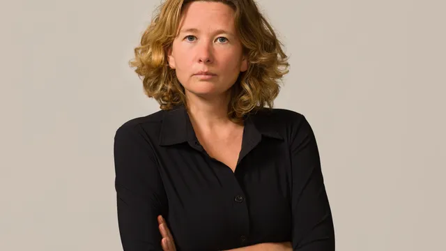 Een vrouw met kort blond krullend haar voor een neutrale achtergrond