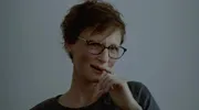 Een van de hoofdpersonen - een vrouw met kort haar - kijkt in de camera