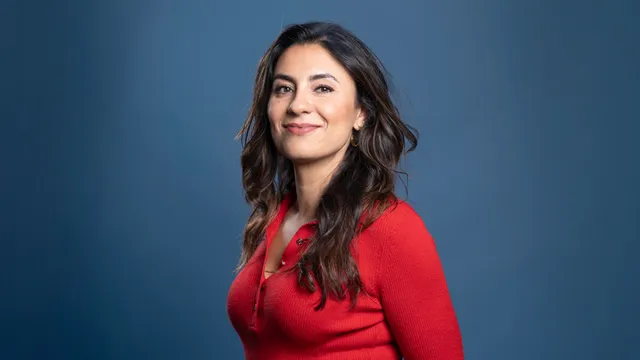 Portretfoto van Nadia Moussaid met een rode long sleeve top aan, bruin half lang haar, voor een blauwe achtergrond