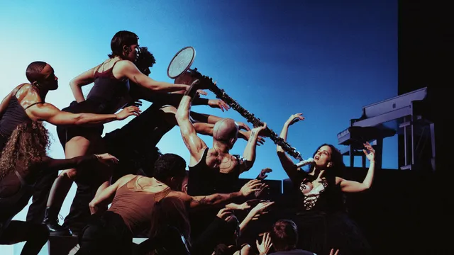Foto van Rosalía omringd door dansers en een microfoon