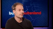 Ot van Daalen kijkt opzij met op de achtergrond het beeld van Bureau Buitenland