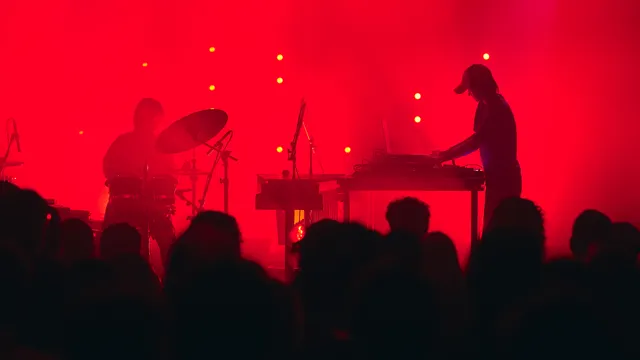 Contouren van drummer en muzikant achter elektronica-tafel