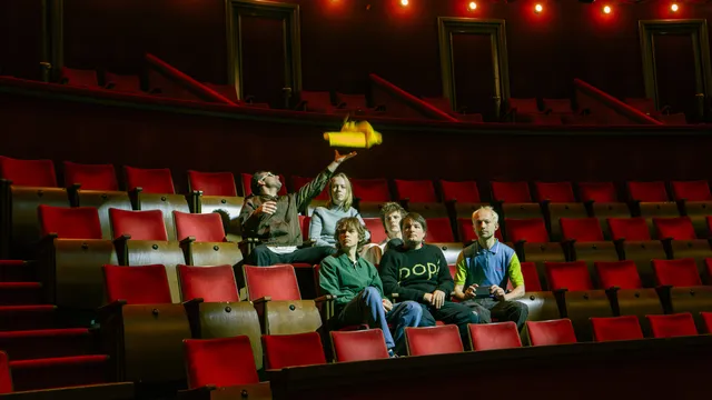 de band personal trainer geportretteerd op de rode stoelen van een theater.
