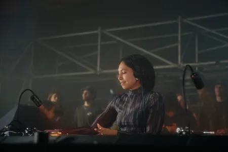 Vrouw met krulletjes lachend achter de draaitafels