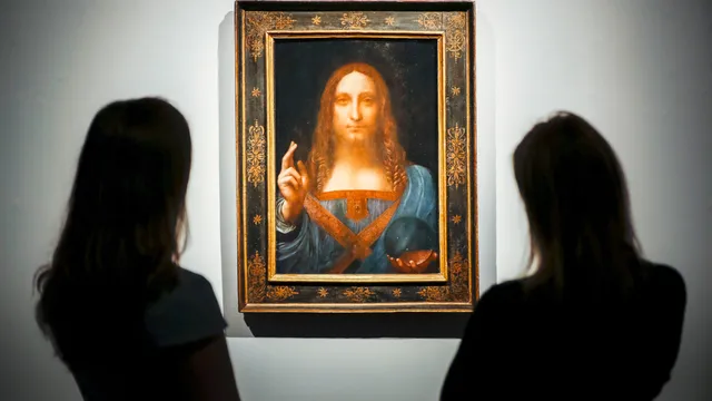 Christie's employees pose in front of a painting entitled Salvator Mundi by Italian polymath Leonardo da Vinci at a photocall at Christie's auction house in central London on October 22, 2017 ahead of its sale at Christie's New York on November 15, 2017.  Salvator Mundi, one of fewer than 20 known paintings by da Vinci, and the only one in private hands, will be offered for sale in Christie's Post-War And Contemporary Art Evening Sale in New York and is estimated to realise in the region of  100 million USD (85 million euro; 76 million GBP).