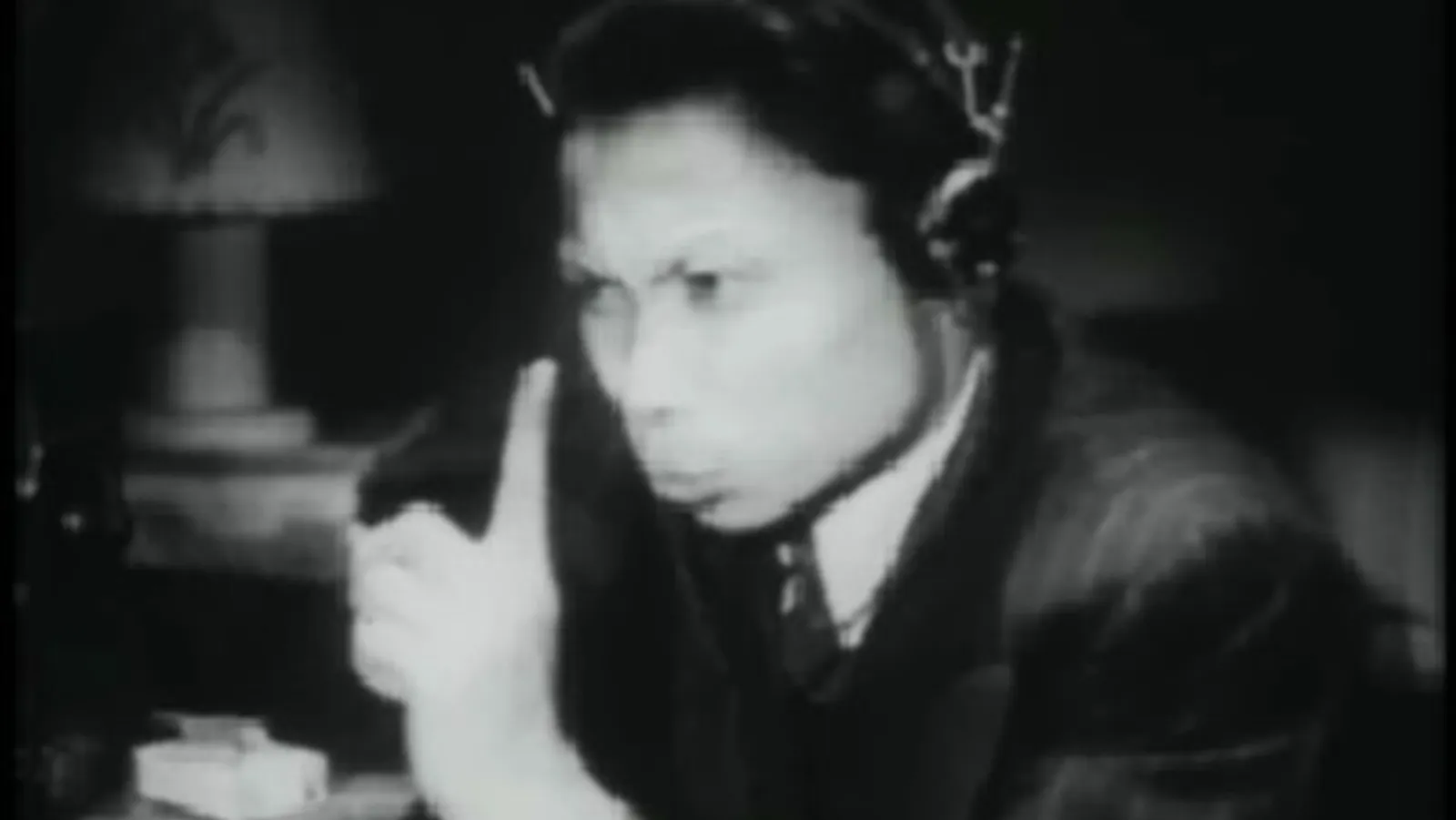 zwart-wit foto van Roelof Kiers met een koptelefoon op en een vinger opsteekt