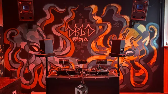 draaitafel met speakers, op de achtergrond een muur met graffiti waarop ook 'DRLD RADIO' te zien is