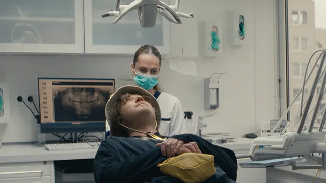 Een man op een tandartsstoel met een buckethat op