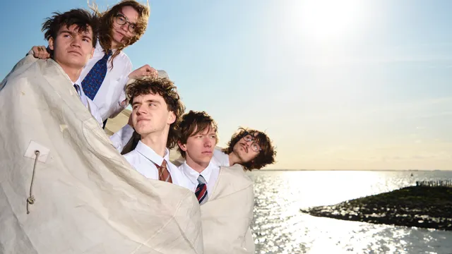 Grote geelstaart de band geposeerd voor de zee gewikkeld in een doek