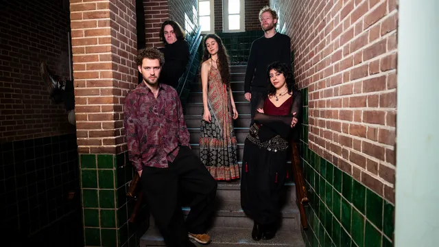 Foto van de hele band Fay + the Maneads op een trap in een oud schoolgebouw