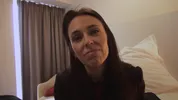 Een vrouw met lang donker haar kijkt recht in de camera met een rustige, vriendelijke uitdrukking.