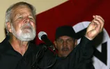 Eugène Terre'Blanche in 2004, met op de achtergrond de vlag van de Afrikaner Weerstandsbeweging
