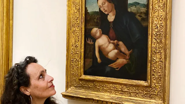 Olga Majeau kijkt naar een schilderij in een goudenlijst