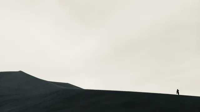 Zwart-wit foto van persoon die in de woestijn loopt.