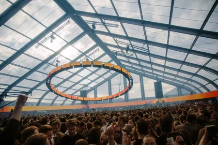 Tent vol mensen met een cirkelvormige lichtinstallatie die oranje licht afgeeft