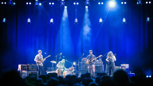 Vier mensen op een rijtje op het podium, blauw licht