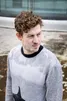 Lucas Derycke kijkt opzij. Hij heeft een grijze sweater aan. Het is een staand beeld.