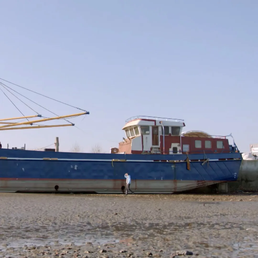 Grote vissersboot die half in beeld is en die op het droge ligt.