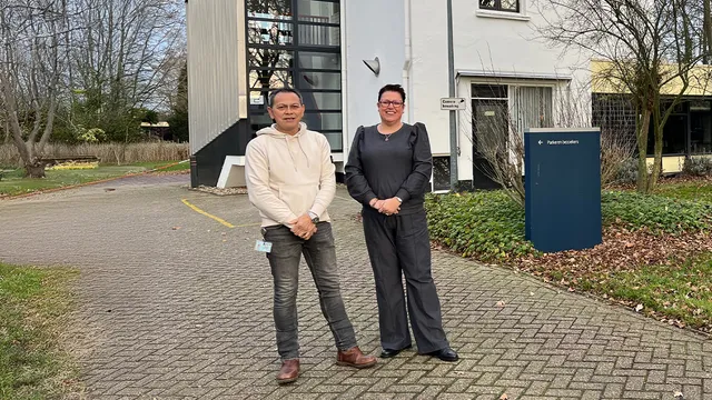 Twee mensen, een man en een vrouw, staan voor het gebouw van Het Huis van Herstel.