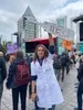Een vrouw in witte doktersjas houdt een protestbord omhoog met daarop de tekst: De aarde heeft koorts