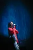 Mitski in rood pak in AFAS Live voor een blauw gordijn