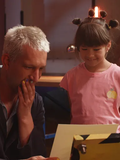 Presentator Maarten Bel kijkt samen met een kind naar een kunstwerk in zijn handen.