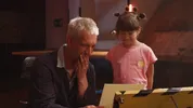 Presentator Maarten Bel kijkt samen met een kind naar een kunstwerk in zijn handen.