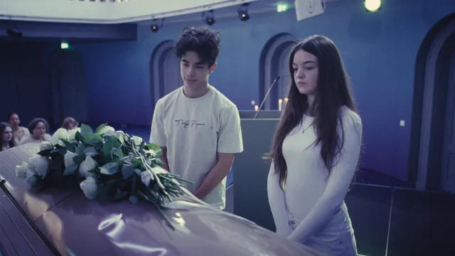 Een jonge man en vrouw staan naast een doodskist