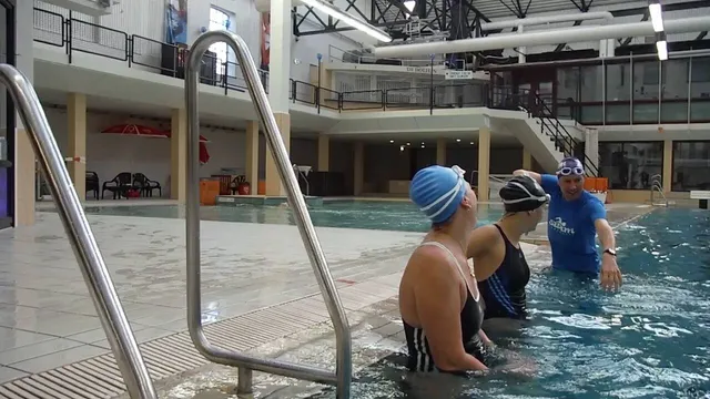 Zwemcoach Giel Veggelaar geeft zwemsters uitleg in het zwembad