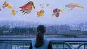 Rug van een meisje met zwart haar in een staart, ze kijkt naar een industrieterrein. Boven haar kindertekeningen van vogels.