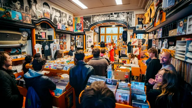 Mensen kijken in een platenzaak naar een optreden