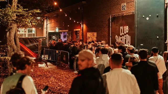 Mensen staan bij nacht in de rij voor de oude Club Smederij