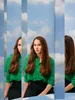 Nasrah Habiballah vanuit drie perspectieven te zien voor een achtergrond die bestaat uit blauwe lucht en wolken.