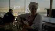 Een jonge vrouw met traditionele haardracht zit met een gitaar op schoot in een rustplaats voor IDF-soldaten