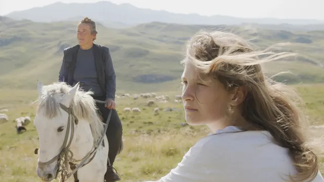 Links een man op een wit paard in de bergen en rechts het hoofd van een blonde vrouw.