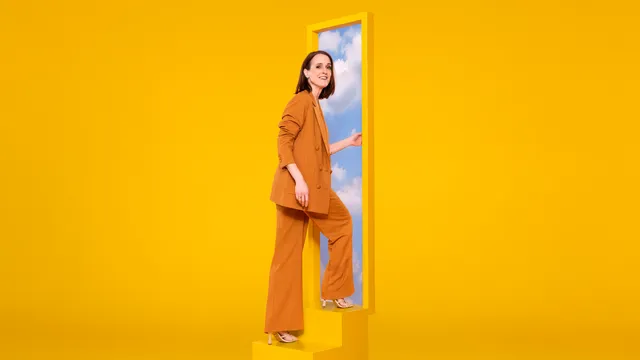 Janine Abbring in een gele ruimte op een trap naar de lucht.