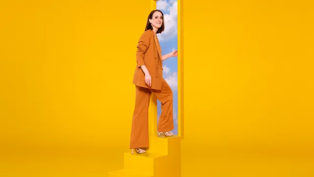 Janine Abbring in een gele ruimte op een trap naar de lucht.