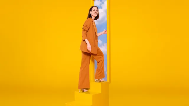 Janine Abbring in een gele ruimte op een trap naar de lucht.